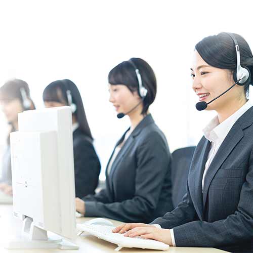 ヘッドセットを着けてパソコンで作業している保険代理店のスタッフの様子